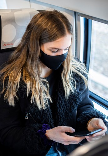 Tjej med munskydd på tåget