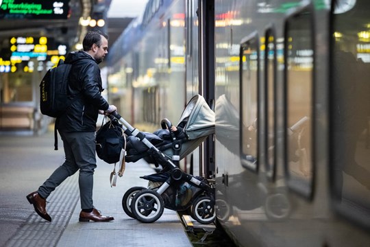 Man med barnvagn på väg ombord på tåget