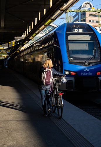 Kvinna med cykel på väg till tåget