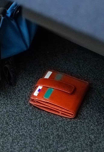 A lost wallet lays on the floor beneath a seat
